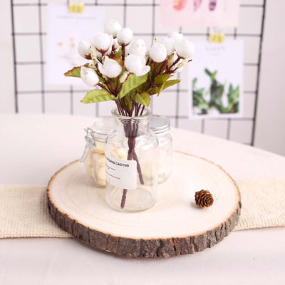 Decorative faux flower arrangement in glass jar on wooden slice.