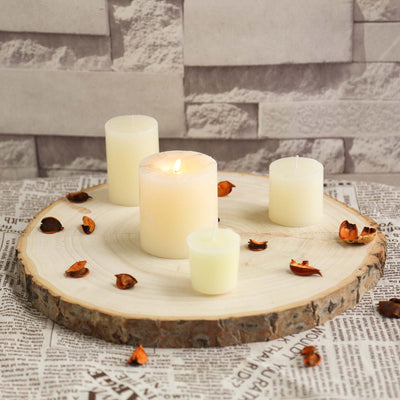 Candles arranged on a wooden slice with dried petals on a newspaper backdrop.