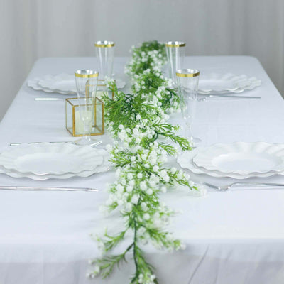 Elegant table setting with white plates and floral centerpiece.