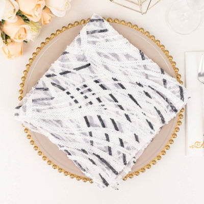 White and black sequined table napkin on a decorative plate.