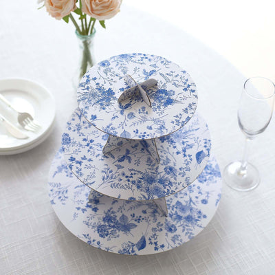 Three-tiered floral cake stand in blue and white on a table setting.