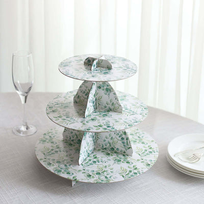 Three-tiered decorative cake stand with floral design on a table setting.