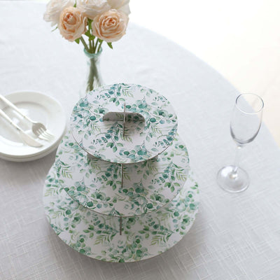 Three-tiered cake stand with green leaf design on a white backdrop.