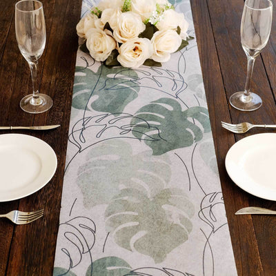 Table runner with green leaf design on a wooden dining table with plates and glasses.