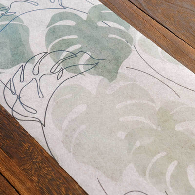 Monstera leaf pattern runner on wooden table surface.