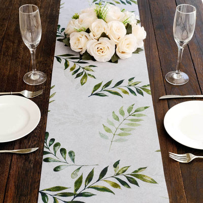 Floral table runner with greenery design on a wooden dining table setting.
