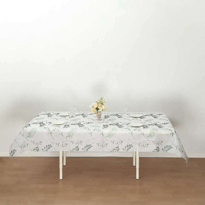 Floral tablecloth on a dining table with plates and a vase of flowers.