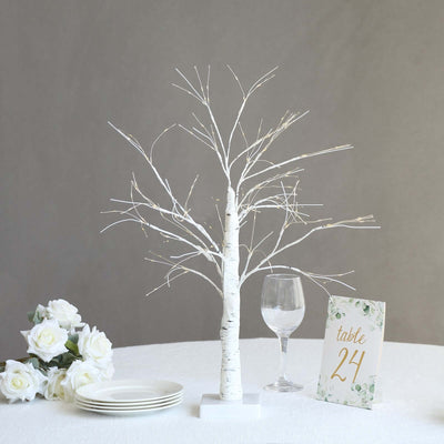 White decorative tree centerpiece with table number sign and floral accents.