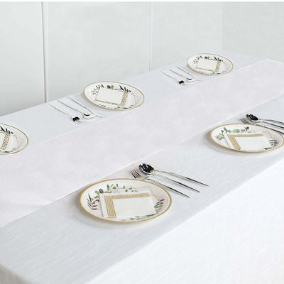 Elegant dining set with decorative plates and cutlery on a white tablecloth.