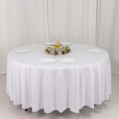 Elegant round table set with white tablecloth and decorative centerpiece.