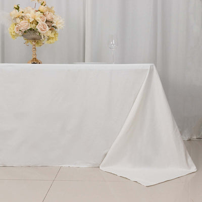 Elegant white tablecloth draped over a table with flowers and a wine glass.