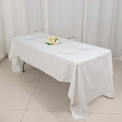 Elegant white table setup with plates and floral centerpiece.