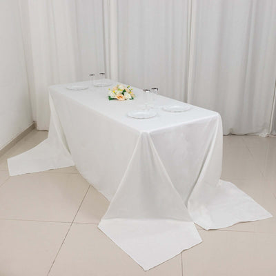 Elegant white table set for dining with plates and floral centerpiece.