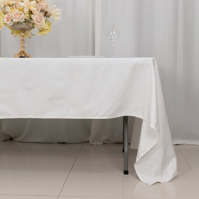 Elegant white tablecloth draped over a table with floral arrangement and glassware.