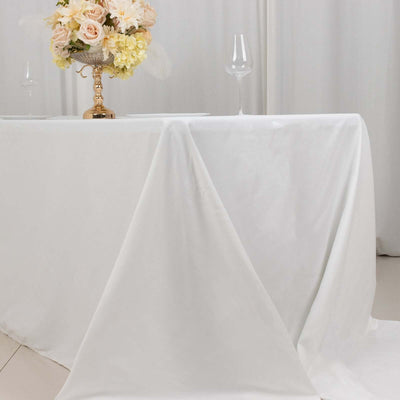 Elegant white tablecloth draping over a table with floral centerpiece and glassware.