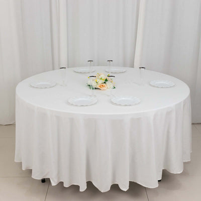Round dining table set with white tablecloth and floral centerpiece.