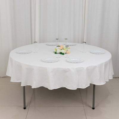 Round table set with white tablecloth and decorative plates.