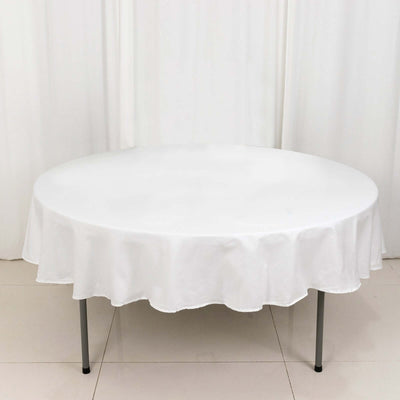 Round white table with a scalloped tablecloth on a plain background