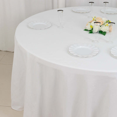 Round table set with white plates and floral centerpiece.