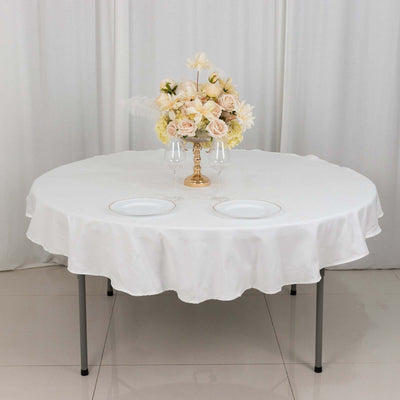 Round table set with a floral centerpiece and plates on a white backdrop.