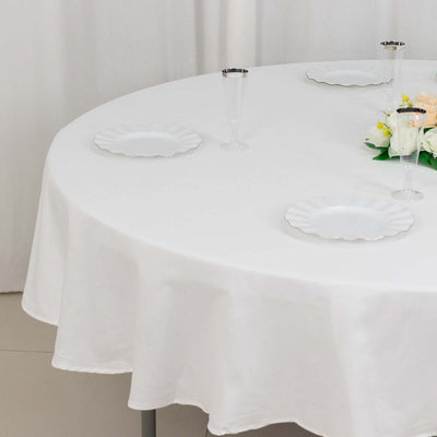 Round table set with elegant white tablecloth and plates.