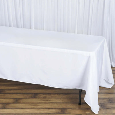 White tablecloth draped over a table on a wooden floor.