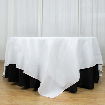White tablecloth draped over a black table skirt in a minimalist setting.