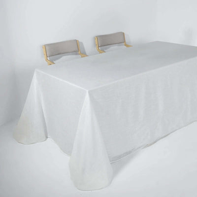 White table with a textured tablecloth and two chairs against a plain background