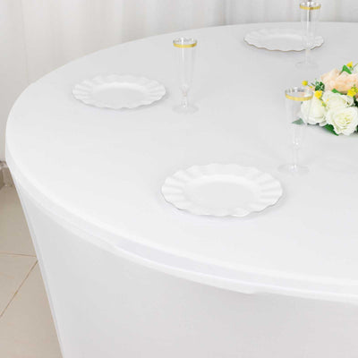 Round white table set with plates and glasses, featuring a floral centerpiece.