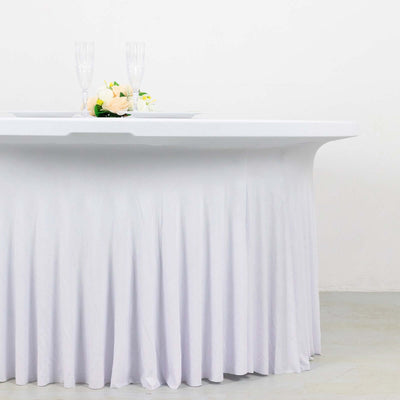 White table with a pleated skirt, set with champagne glasses and floral centerpiece.