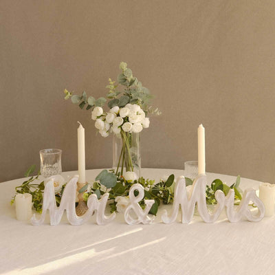 "Mr & Mrs decorative letters with flowers and candles on a table"