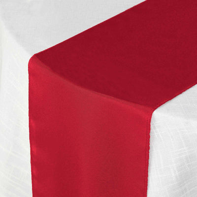 Red satin table runner draped elegantly over a white tablecloth.