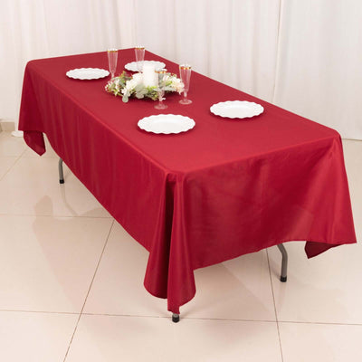 Red tablecloth draped over a table set for a meal with plates and decorations.