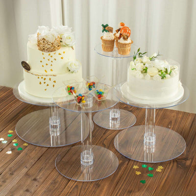 Clear acrylic cake stands with decorative cakes and desserts on a wooden table.