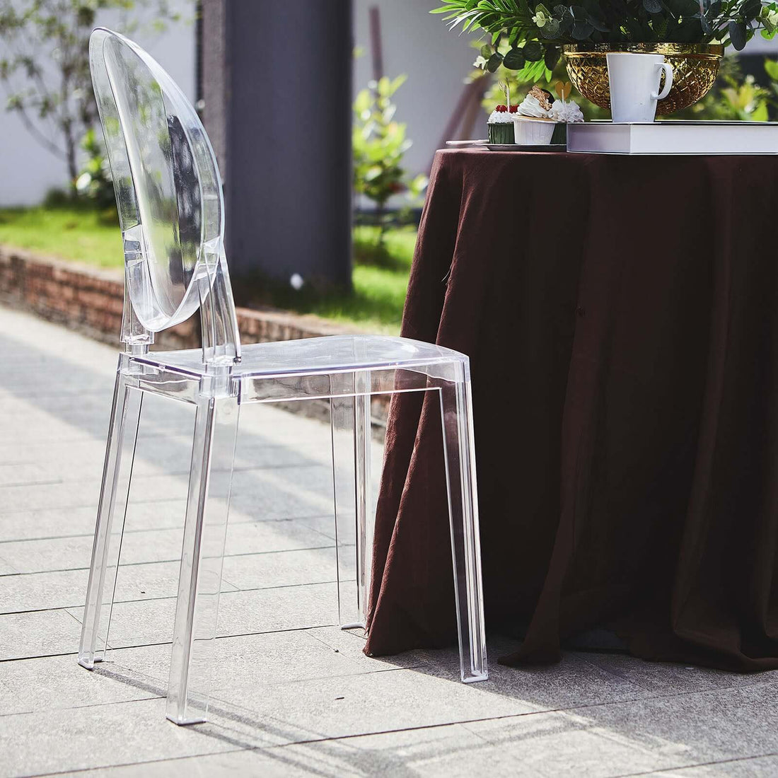 Clear acrylic chair beside a table in an outdoor setting.