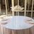 Clear acrylic display stand with floral arrangement on a table.