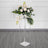 Elegant floral arrangement in a clear pedestal vase.