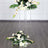 Clear acrylic flower stand with white roses and greenery arrangements.