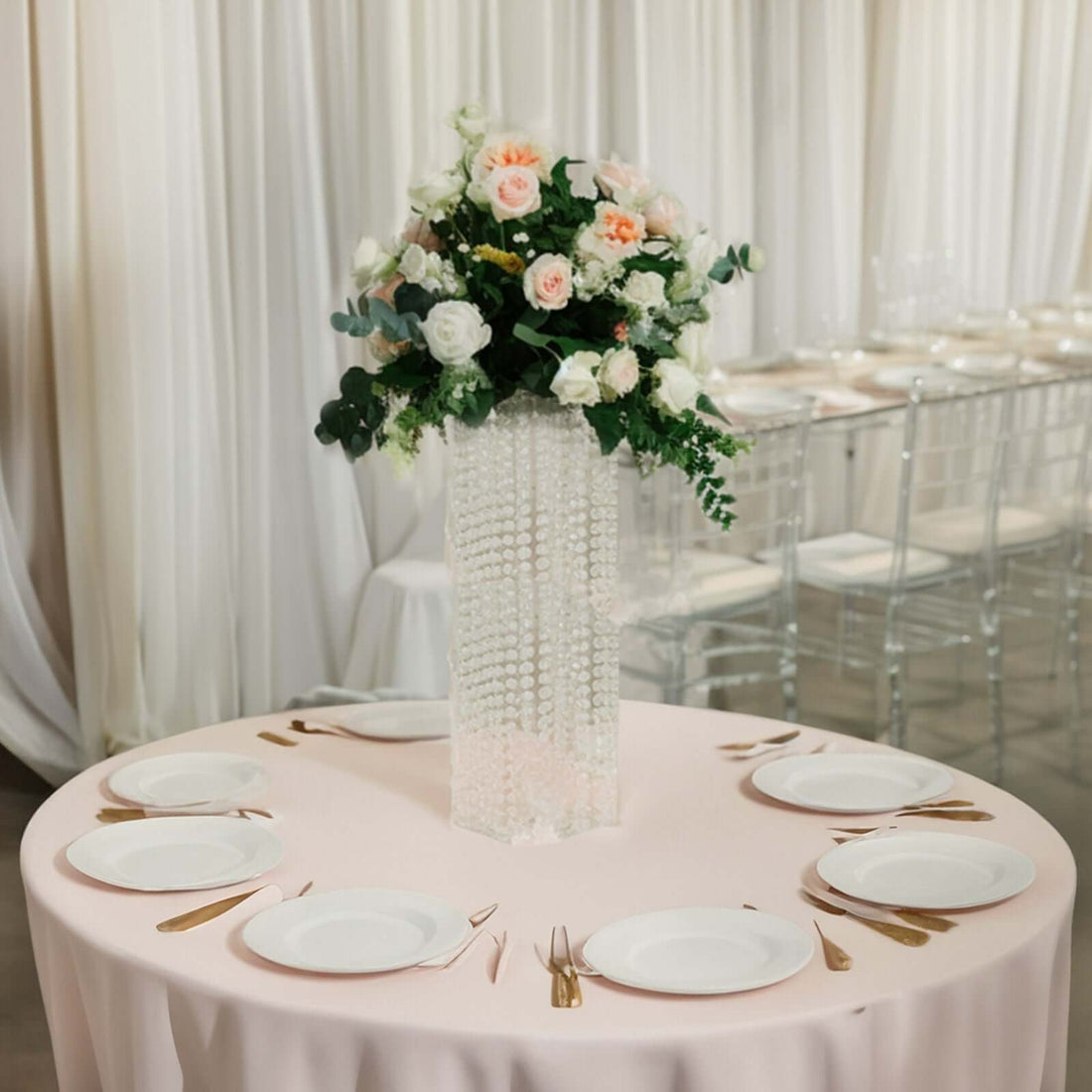 Elegant floral centerpiece on a round table with plates and gold utensils.