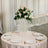 Elegant floral centerpiece on a round table with plates and gold utensils.