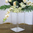 Clear acrylic vase with white roses and orchids, styled with greenery.