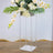 Clear acrylic flower stand with white floral arrangement.