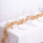 Elegant gold leaf table runner on a white table setting with candles and glassware.