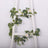 Artificial eucalyptus and rose garland on a white ladder.