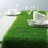 Green grass table runner with white dishware and glasses arranged on a dining table.