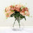 Peach-colored artificial flowers in a clear vase with greenery.