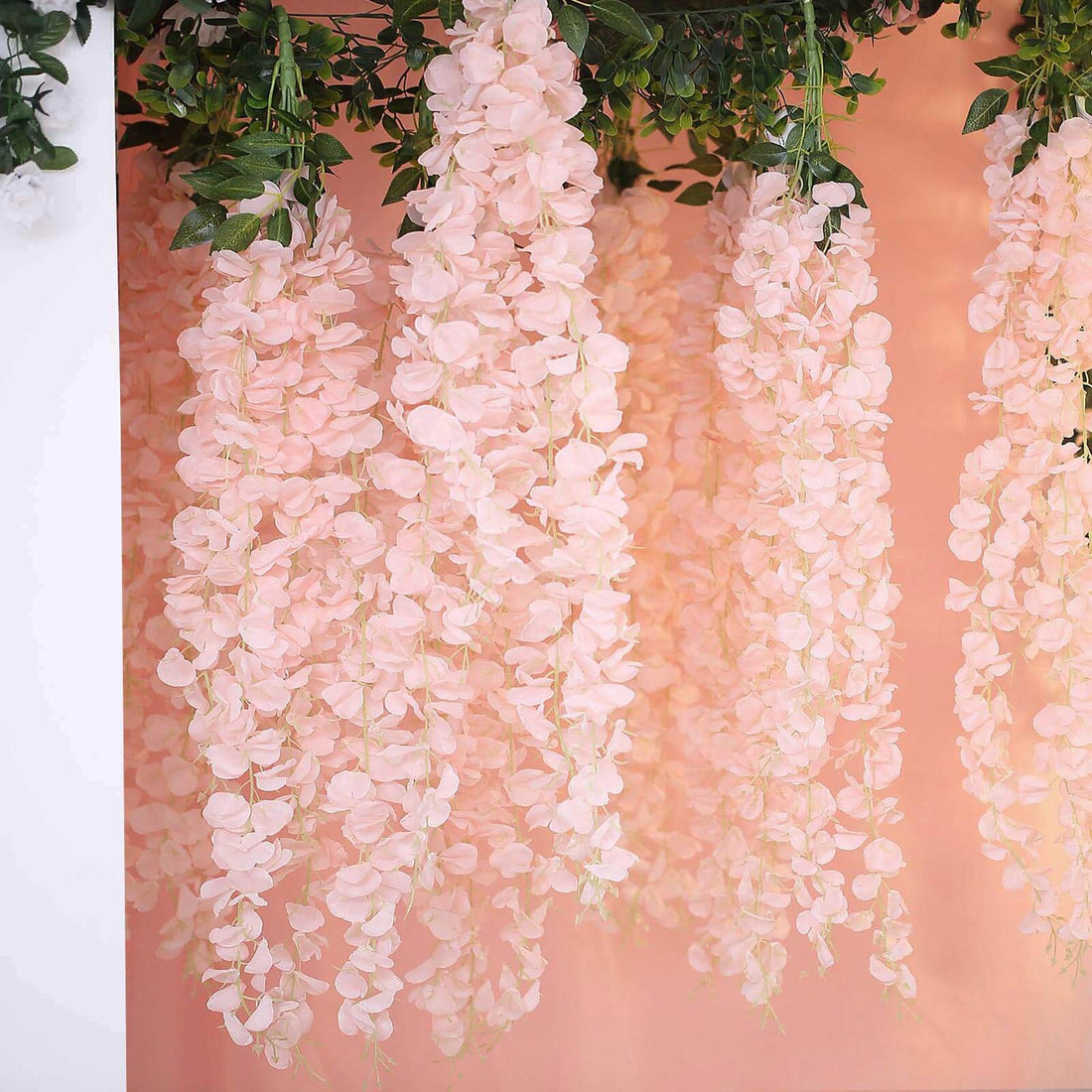 Pink artificial flower garlands hanging against a soft peach backdrop.