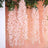 Pink artificial flower garlands hanging against a soft peach backdrop.