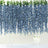 Blue wisteria floral backdrop with hanging vines and a cake in front.