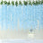 Light blue artificial flower garland background with a white cake and candles.